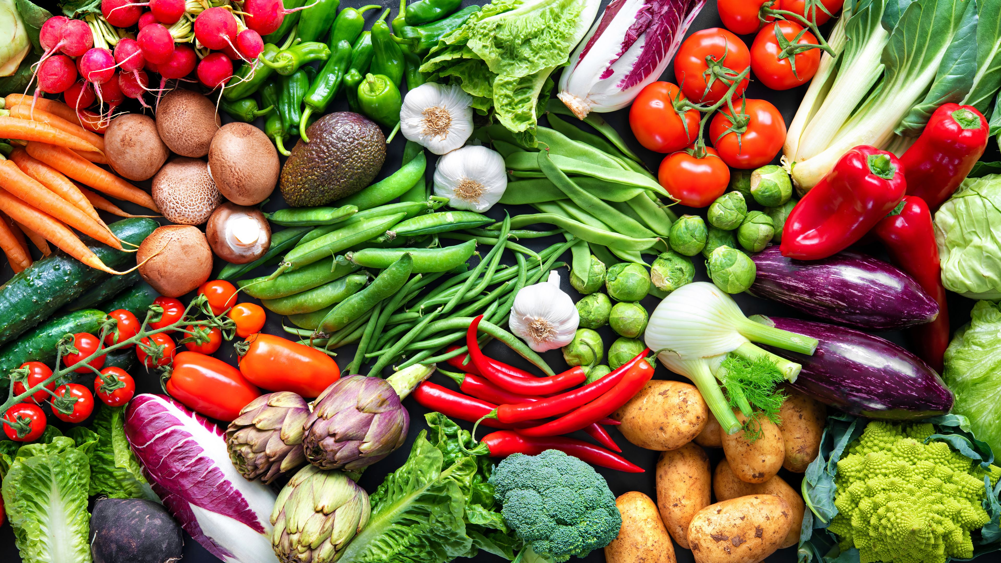 A colorful assortment of fresh vegetables, including carrots, tomatoes, lettuce, radishes, peppers, cucumbers, and more. The vegetables are neatly arranged, highlighting their vibrant hues and variety. The image conveys freshness and a healthy diet.